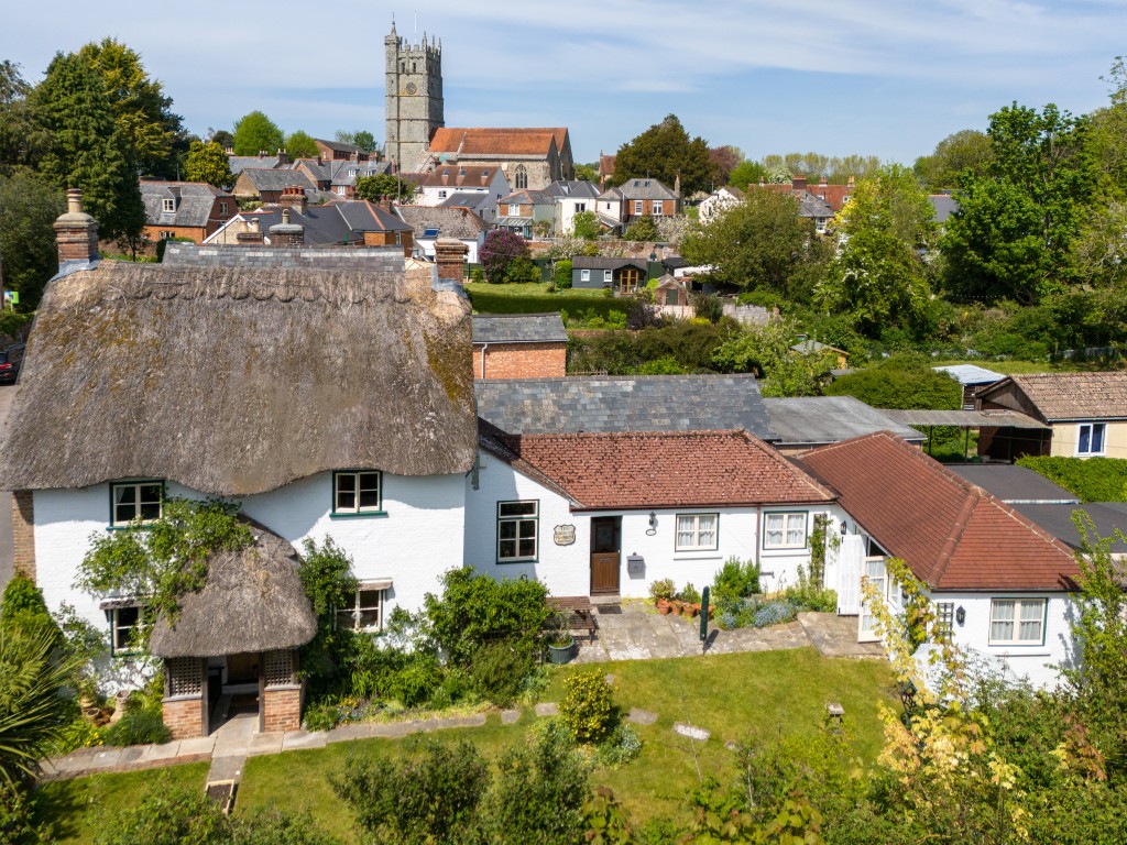 Lot: 108 - CHARMING COTTAGE WITH SELF-CONTAINED ANNEXE, GARDENS AND GARAGE - Aerial view of cottage looking towards castle